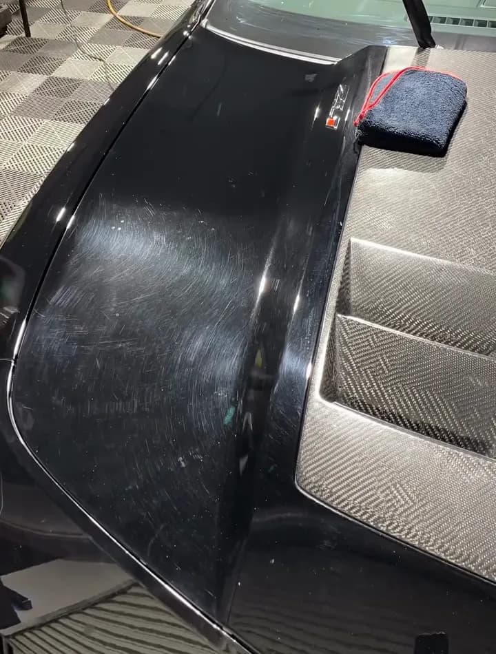 Black wing covered in swirl marks before paint correction
